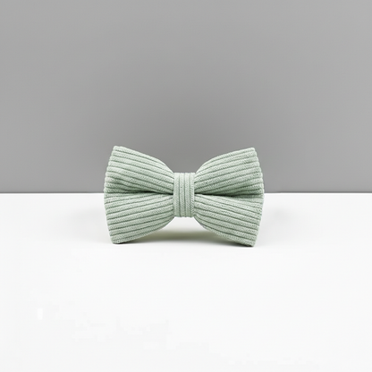 Light green ribbed bow tie on a white surface with a gray background