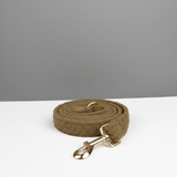 Brown dog leash with gold clasp on a white surface