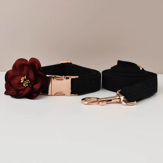Black dog collar with a red flower and rose gold hardware on a light gray background