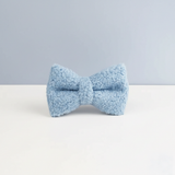 Light blue bow tie on a white surface with a light gray background